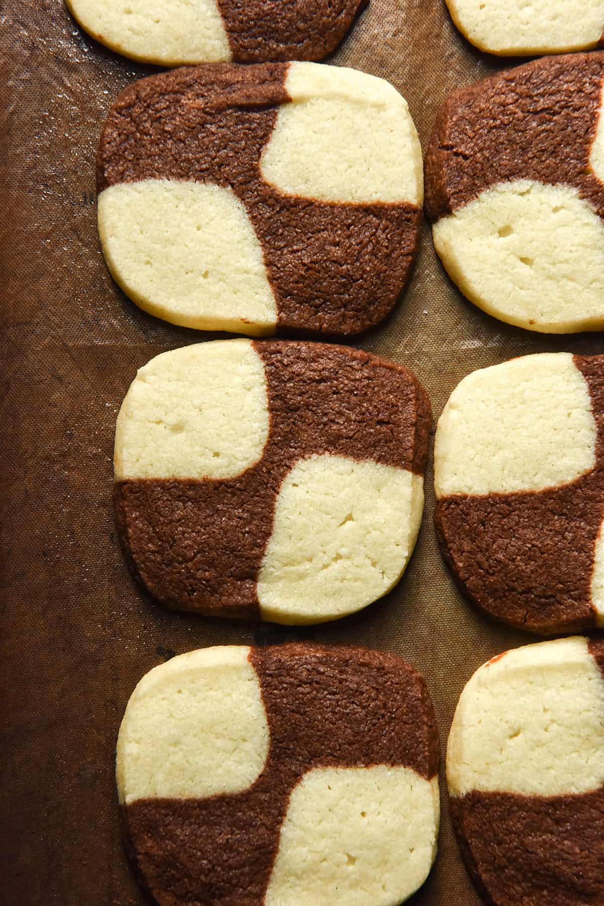 An aerial image of gluten free checkerboard cookies on a baking tray lined with reusable baking paper