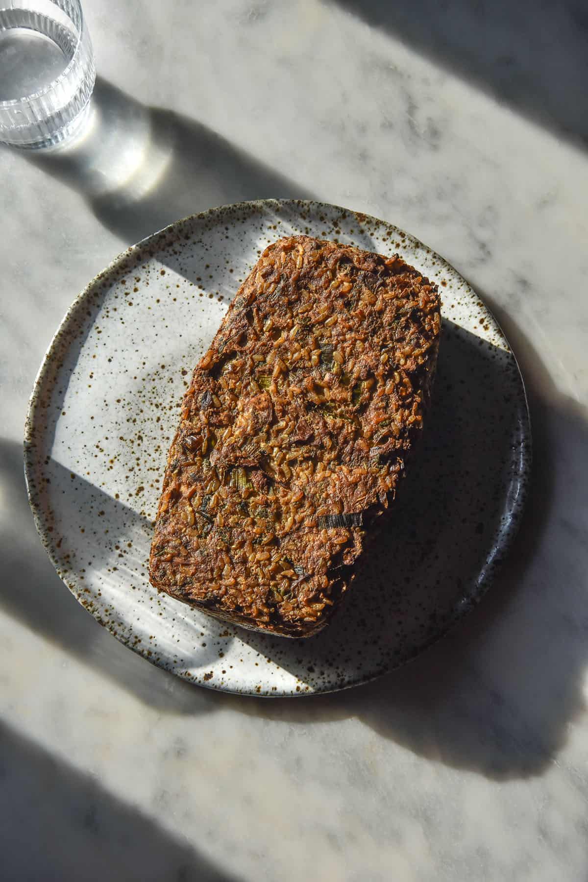 A sunlit aerial image of a low FODMAP vegan meatloaf on a white marble table in contrasting sunlight