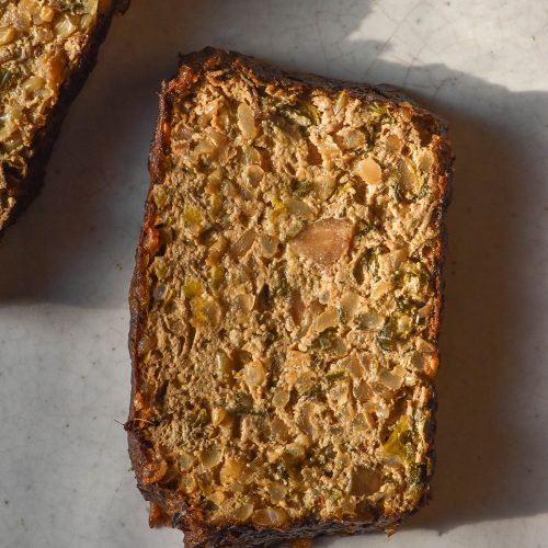 An aerial image of two slices of gluten free vegan nut loaf without nuts on a white ceramic plate