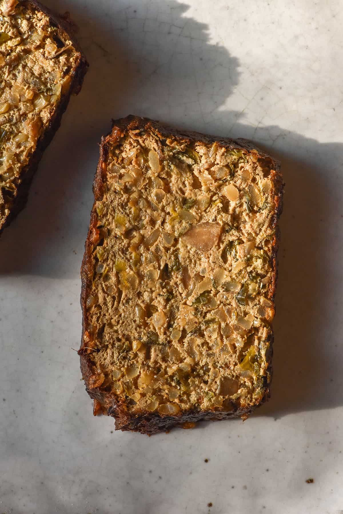 An aerial image of two slices of gluten free vegan nut loaf without nuts on a white ceramic plate