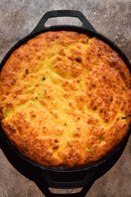 A sunlit aerial image of a low FODMAP cornbread chilli in a black skillet atop a speckled brown backdrop