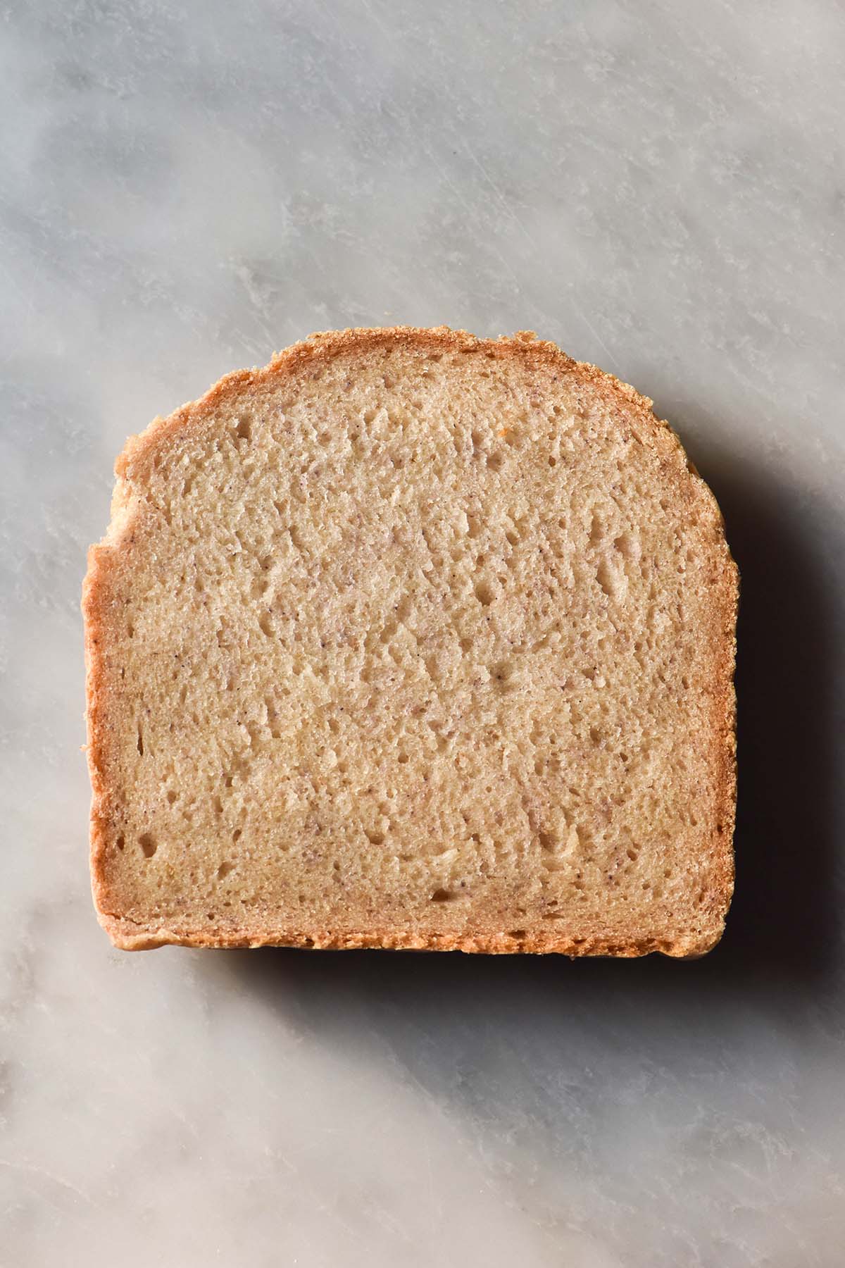 An aerial image of a slice of gluten free egg free bread without yeast atop a white marble table