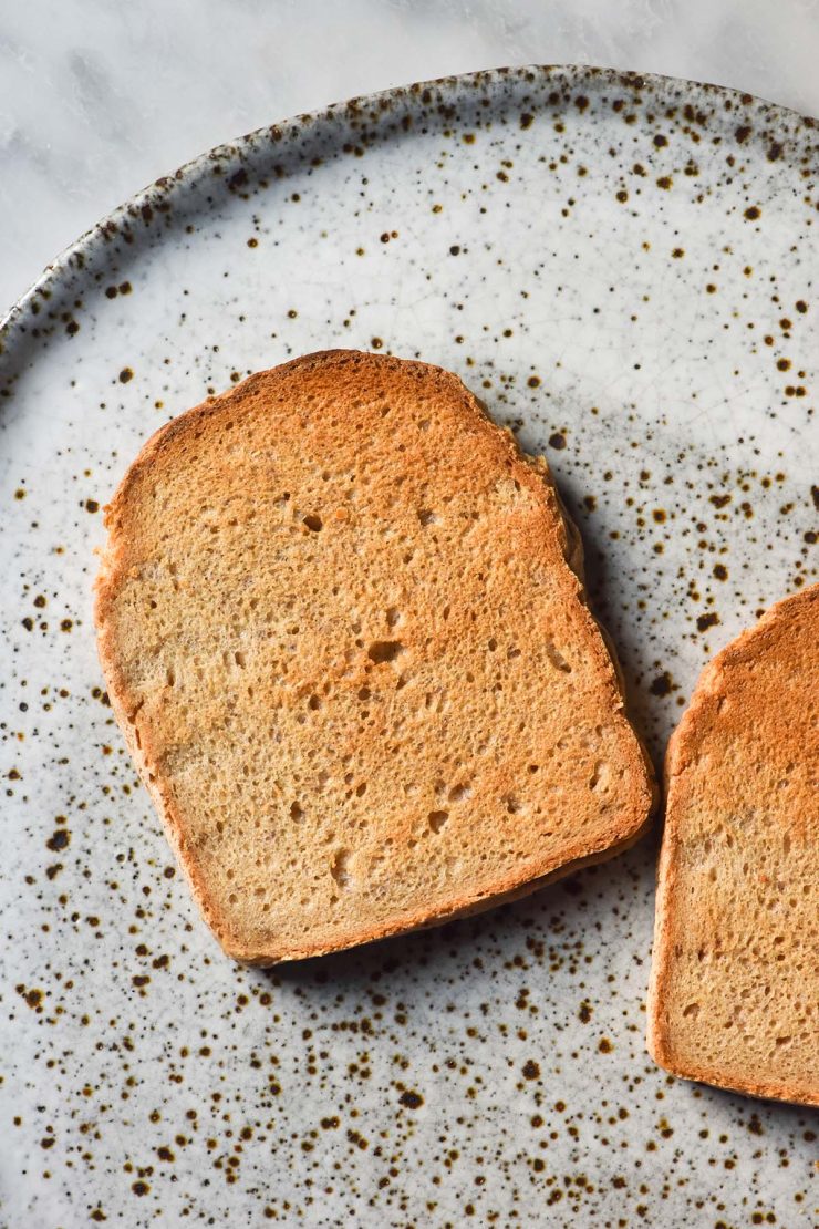 An aerial image of two pieces of gluten free yeast free toast on a white speckled ceramic plate