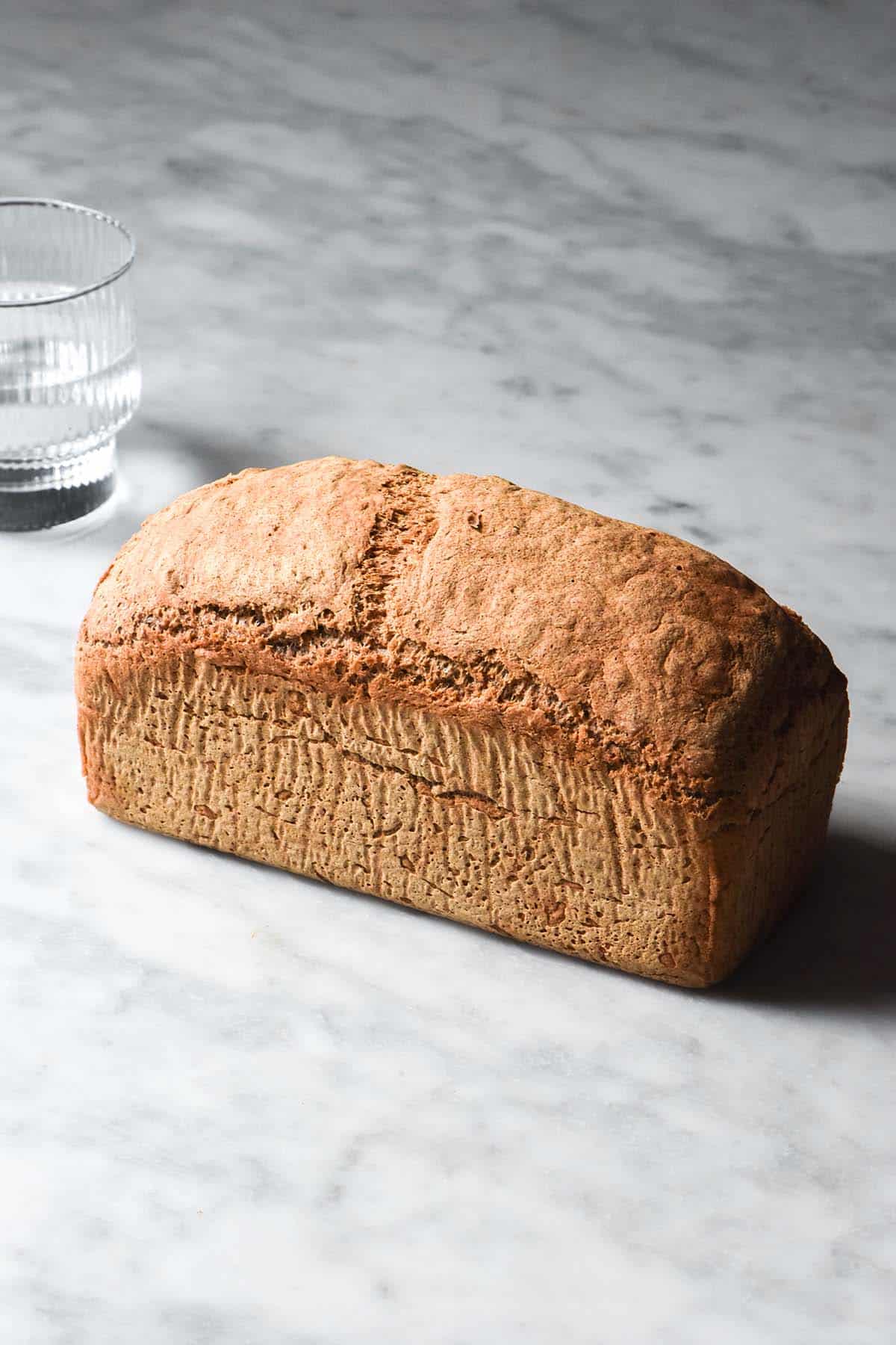 A side on image of a loaf of gluten free yeast free bread atop a white marble table