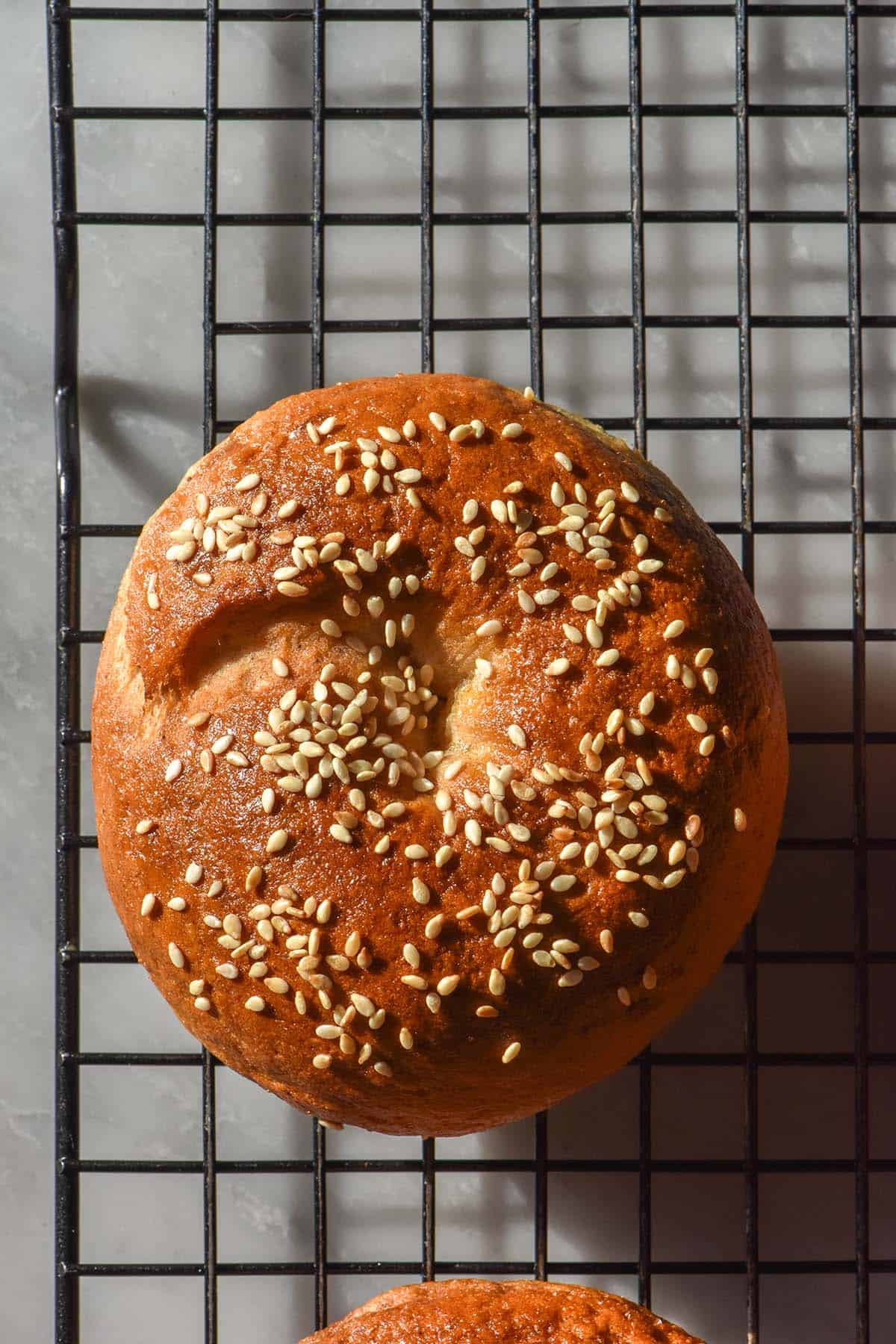 An aerial image of a yeast free gluten free bagel on a wire cooling rack atop a white marble table