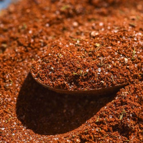 A macro image of low FODMAP jerk seasoning on a spoon top a bright blue ceramic plate