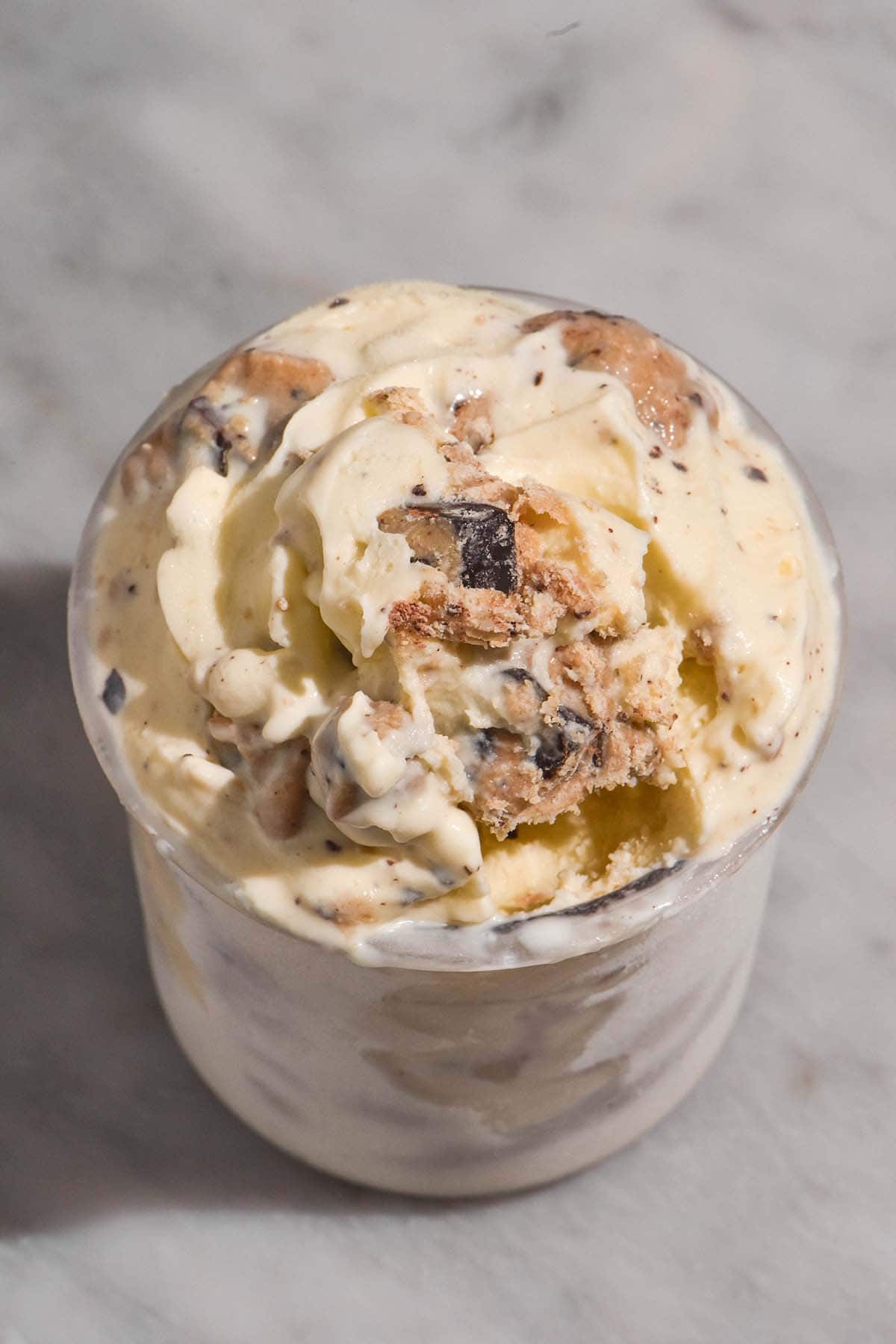 An aerial image of a tub of Ninja Creami cookie dough ice cream on a white marble table
