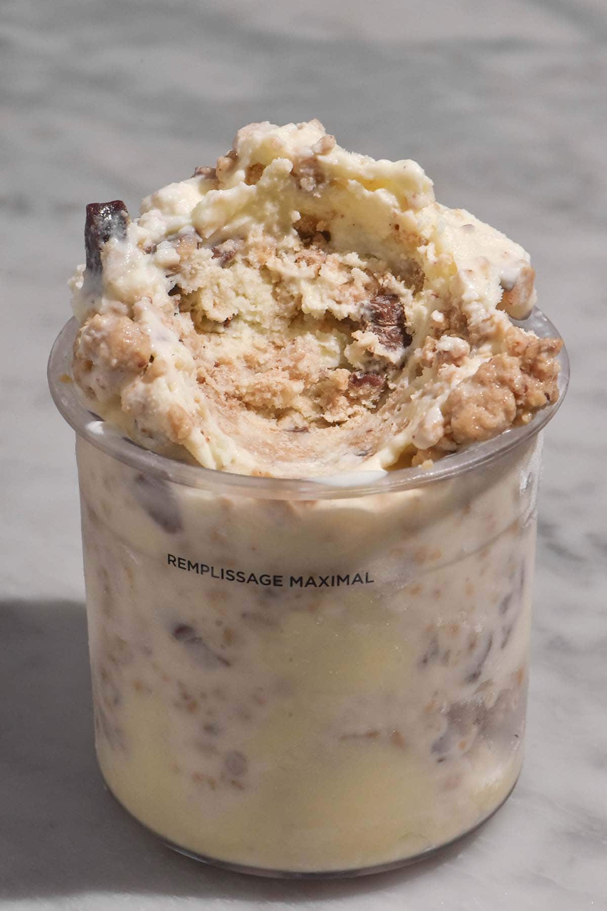 A side on image of a tub of Ninja Creami cookie dough ice cream on a white marble table