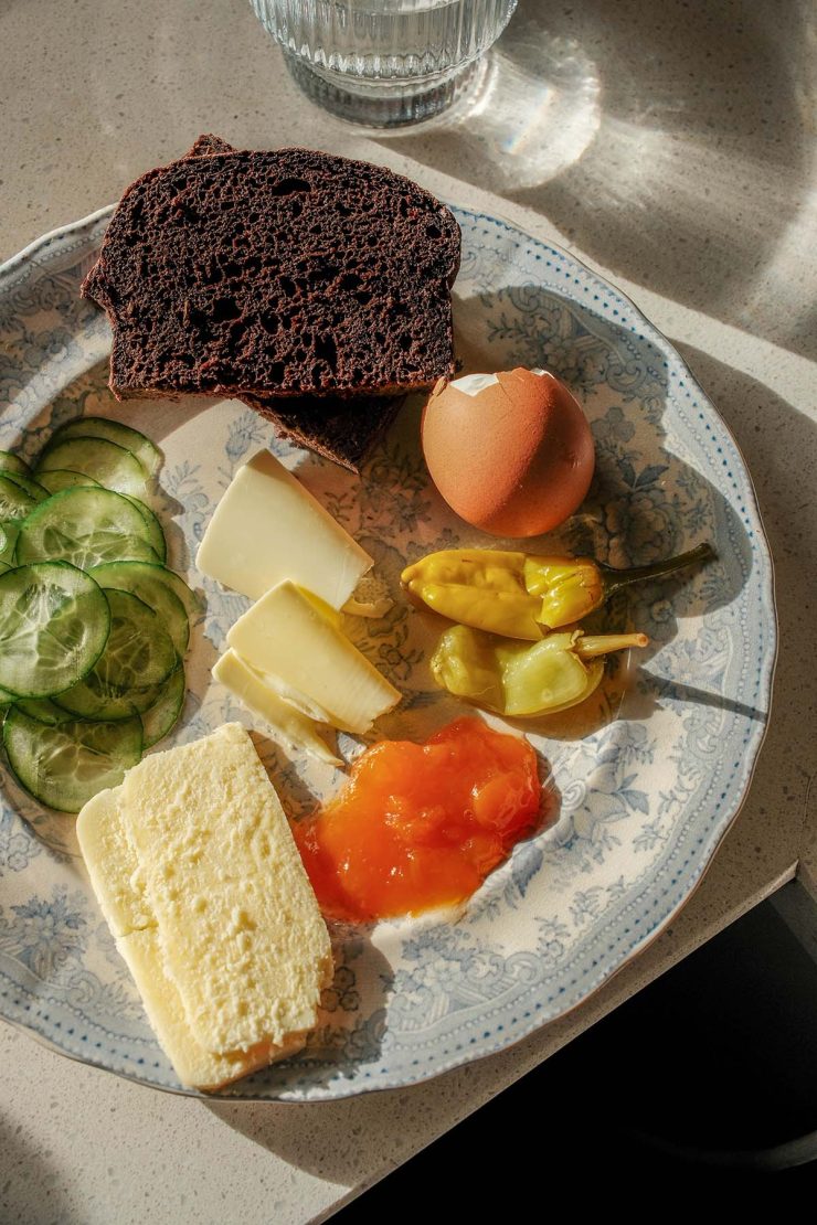 An aerial image of a Scandinavian style snack plate with a slice of gluten free pumpernickel bread. The dish sits atop a sunlight stone bench top