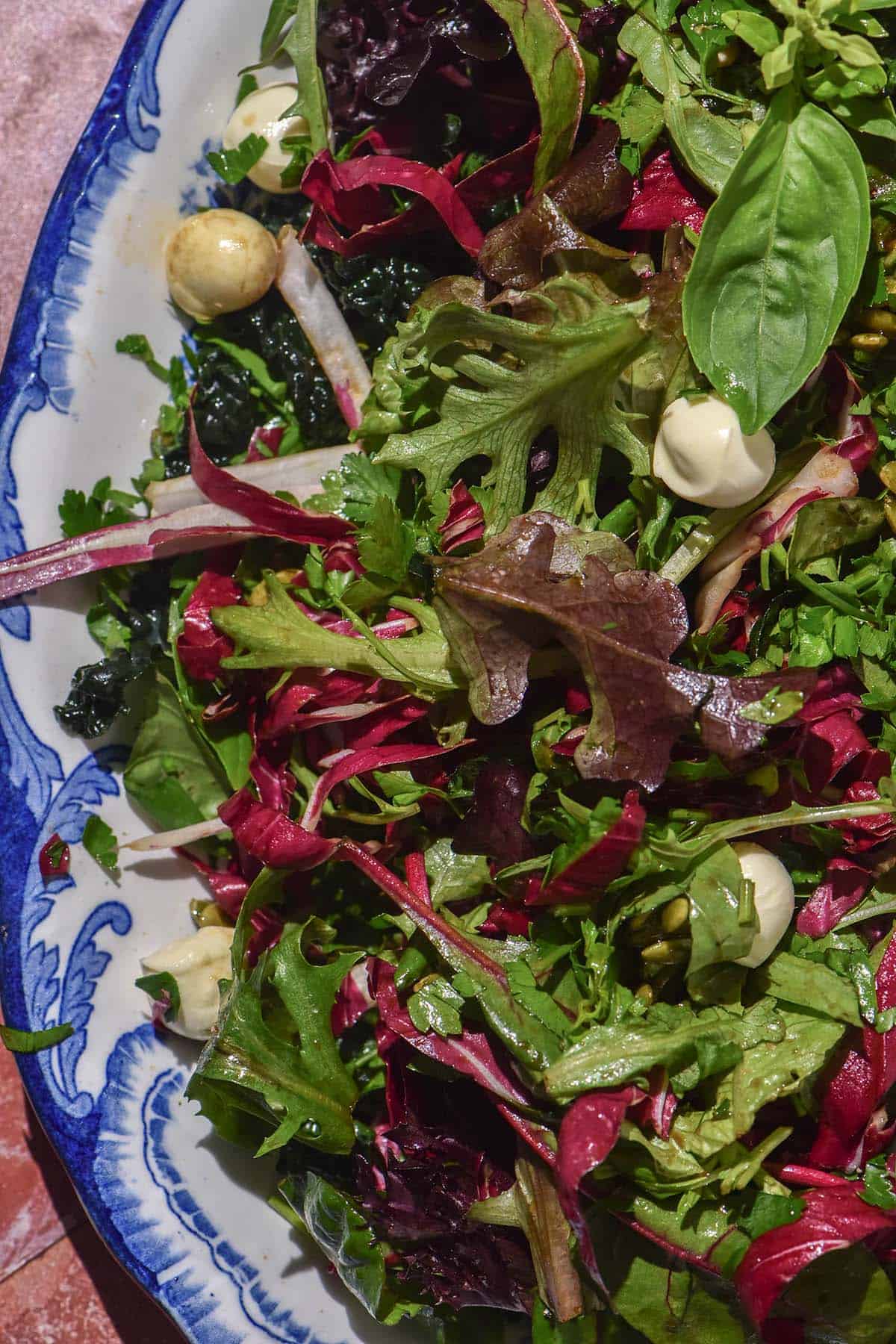An aerial image of a low histamine salad dressed with a low histamine salad dressing on a blue and white scalloped plate