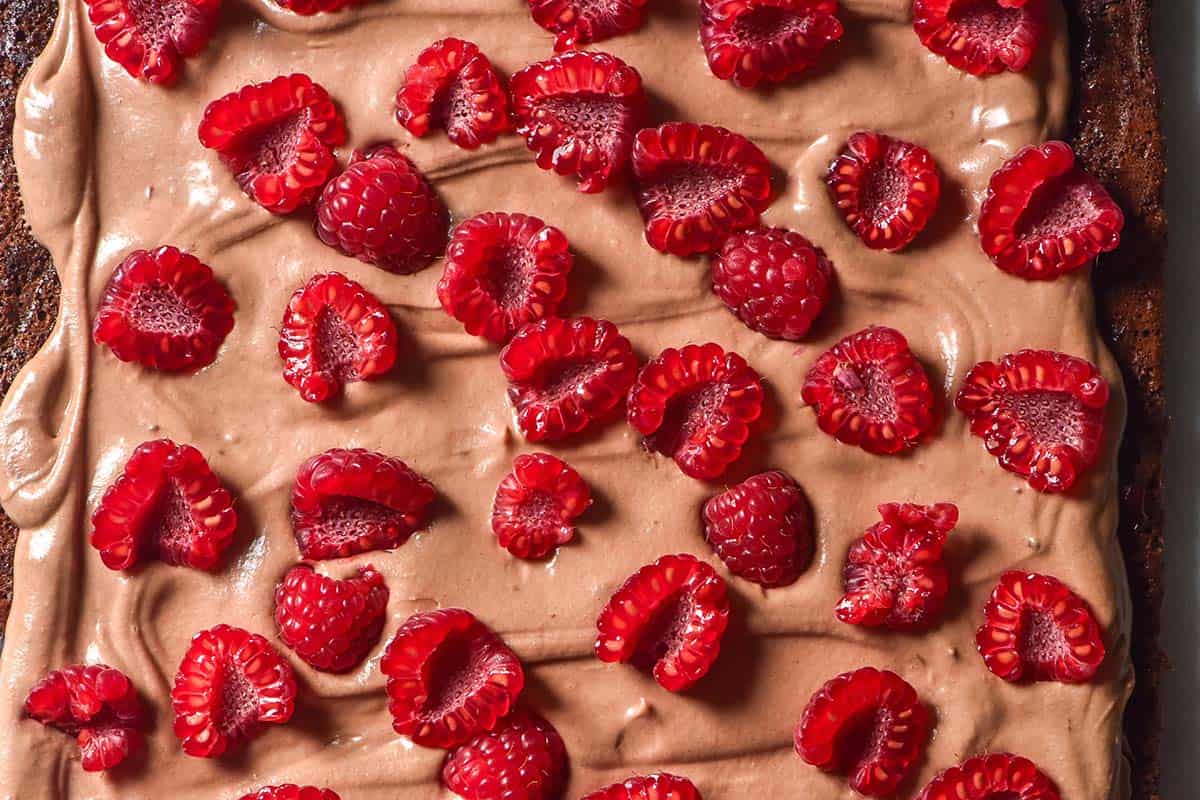 An aerial macro image of a chocolate roulade topped with Nutella mascarpone and fresh raspberries