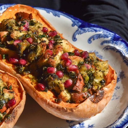 A moody image of a white and blue plate topped with stuffed pumpkins against a dark backdrop