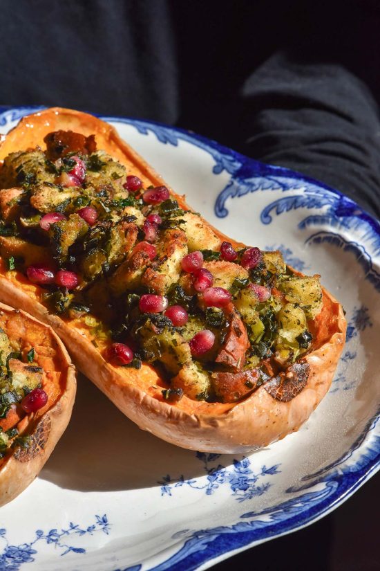 A moody image of a white and blue plate topped with stuffed pumpkins against a dark backdrop
