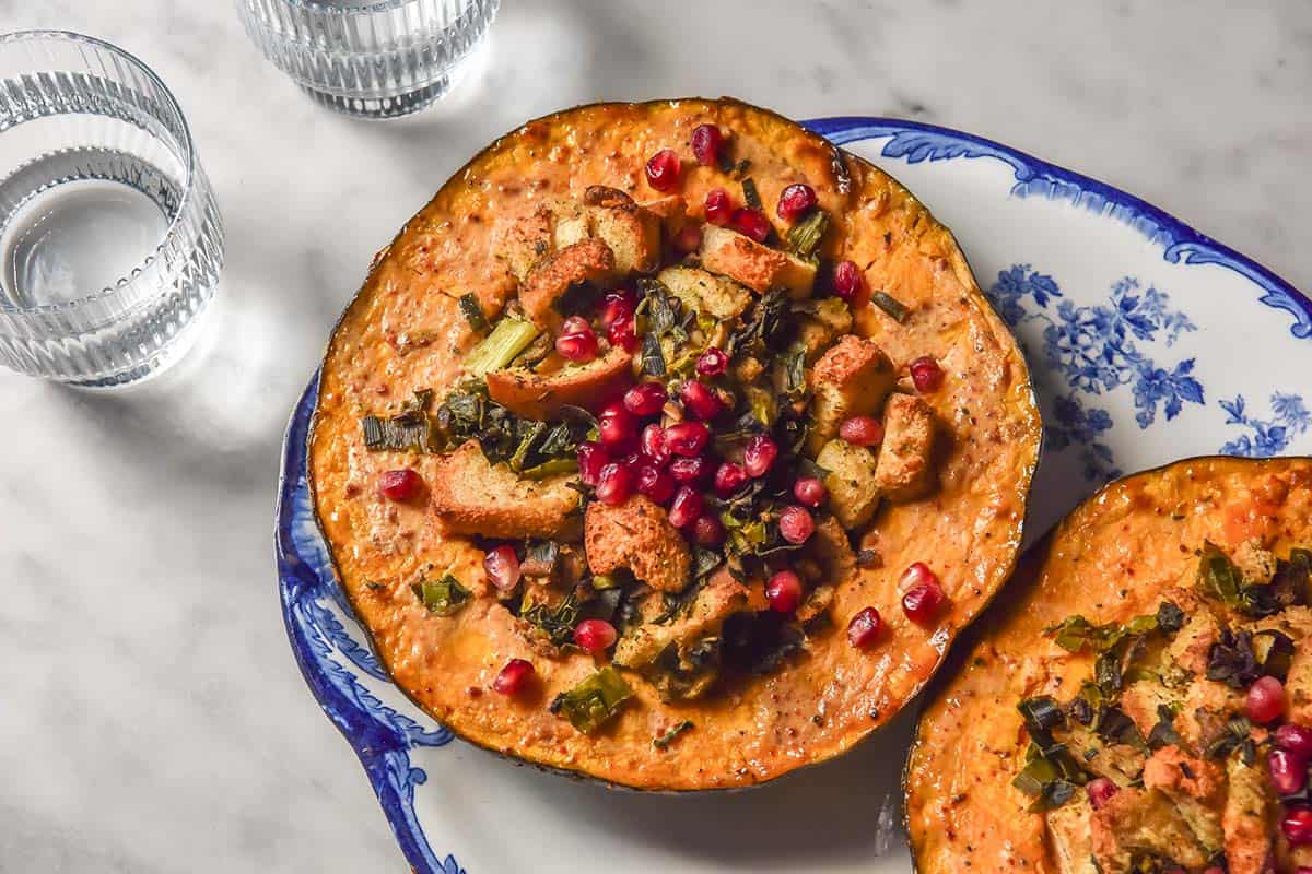 An aerial image of Low FODMAP stuffing filled pumpkins on a blue and white plate atop a white marble table