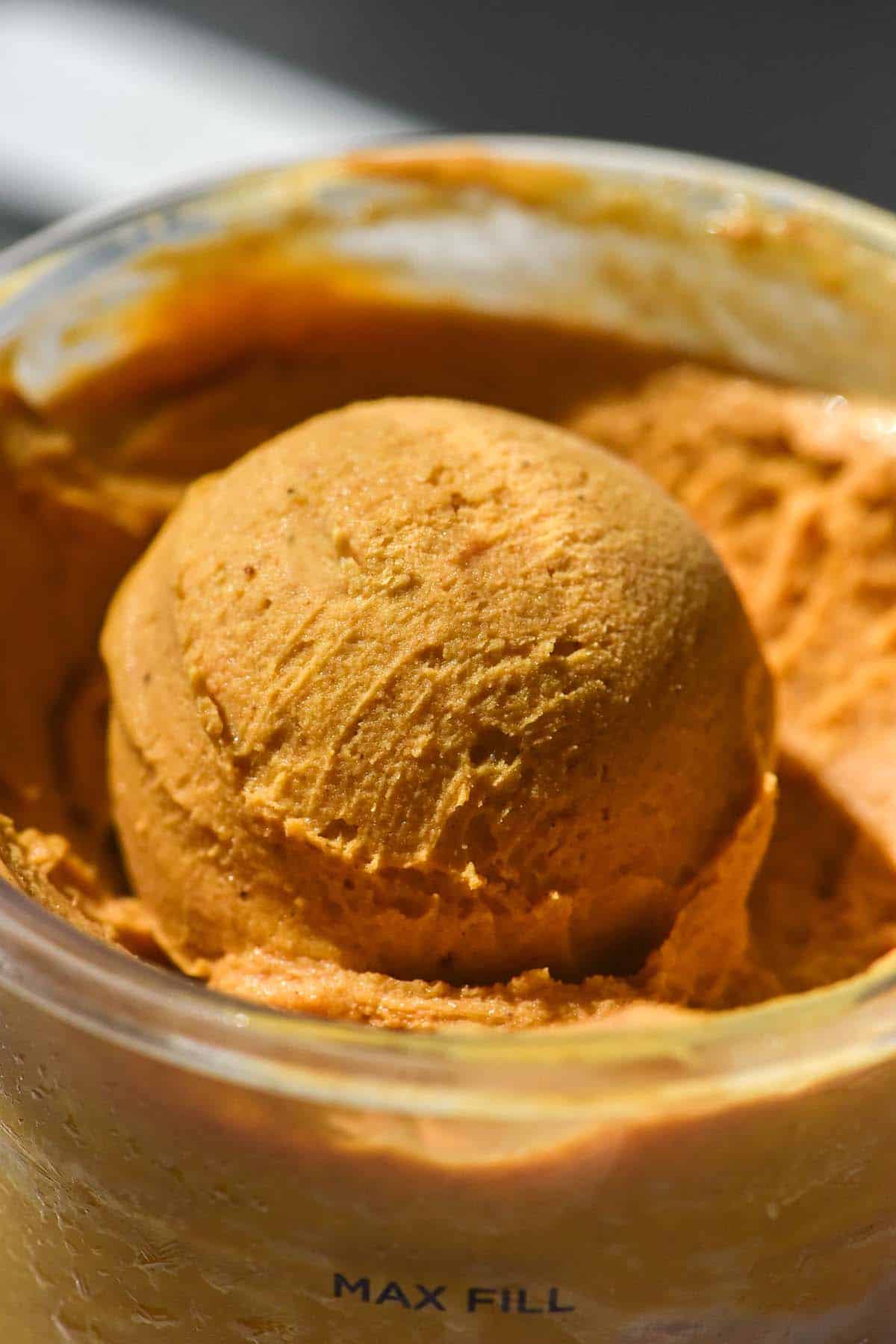 A macro close up image of a scoop of Ninja Creami pumpkin ice cream in bright contrasting light