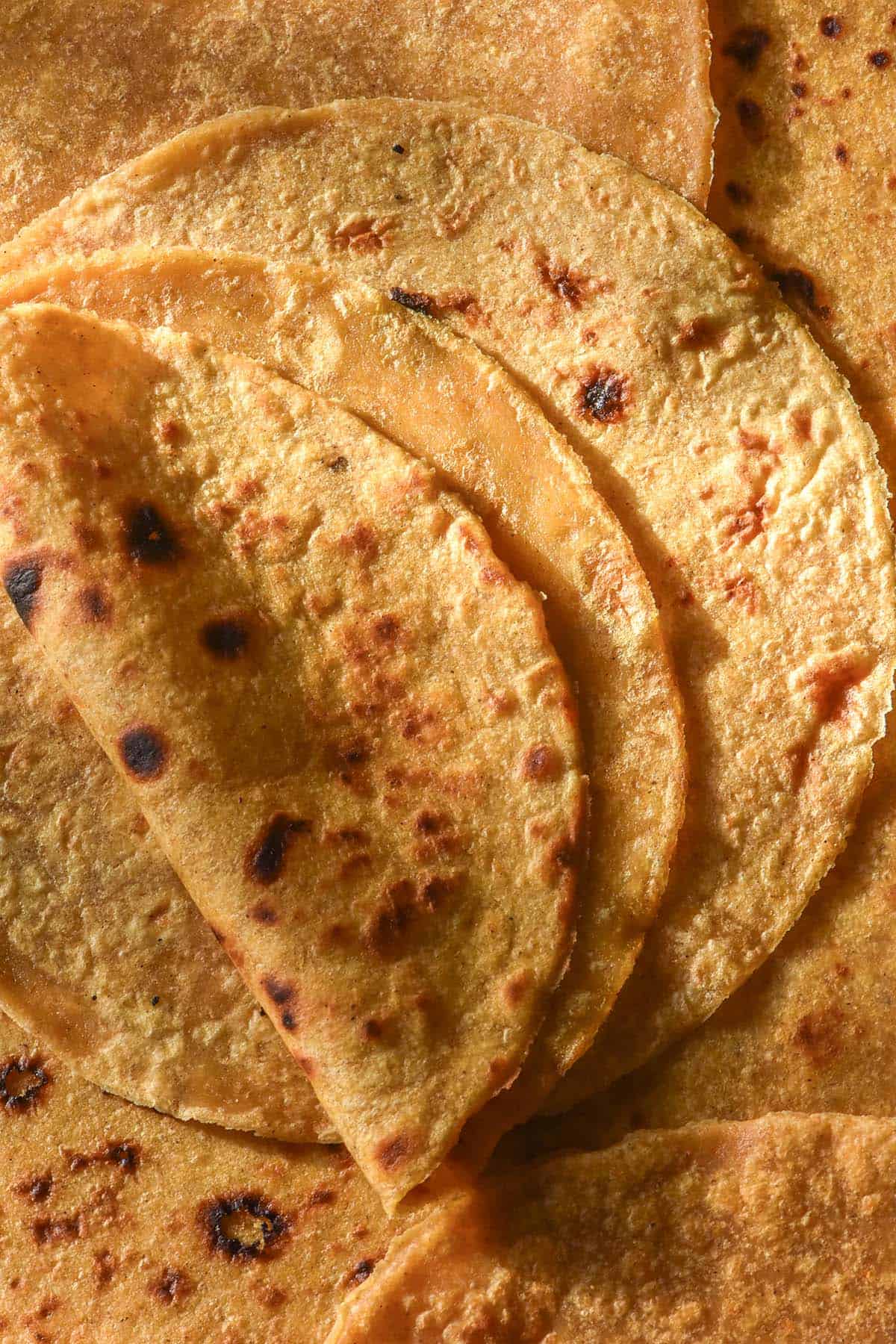 An aerial image of sweet potato tortillas casually arranged in a pile. The top tortilla has been folded in half