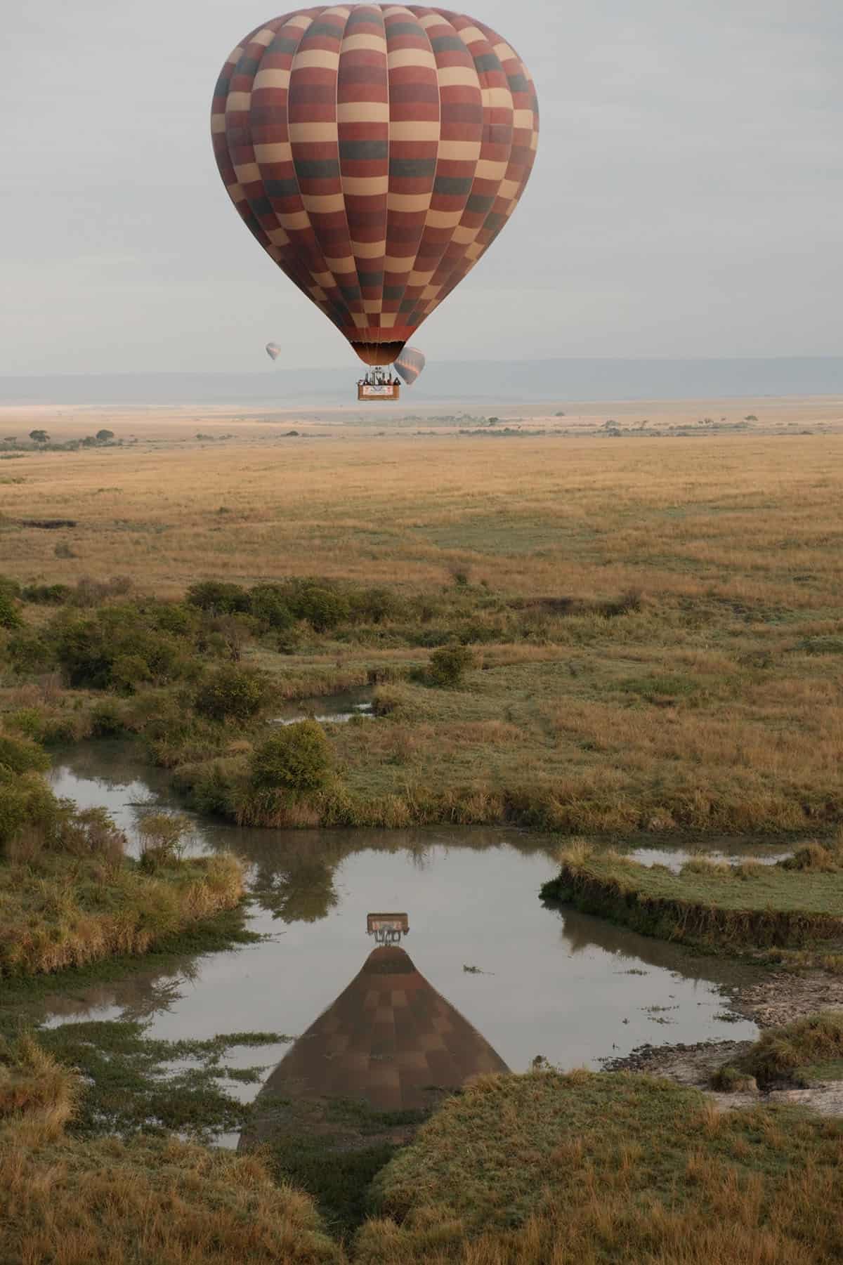 An image of a hot air balloon reflecting on the water in the Masai Mara