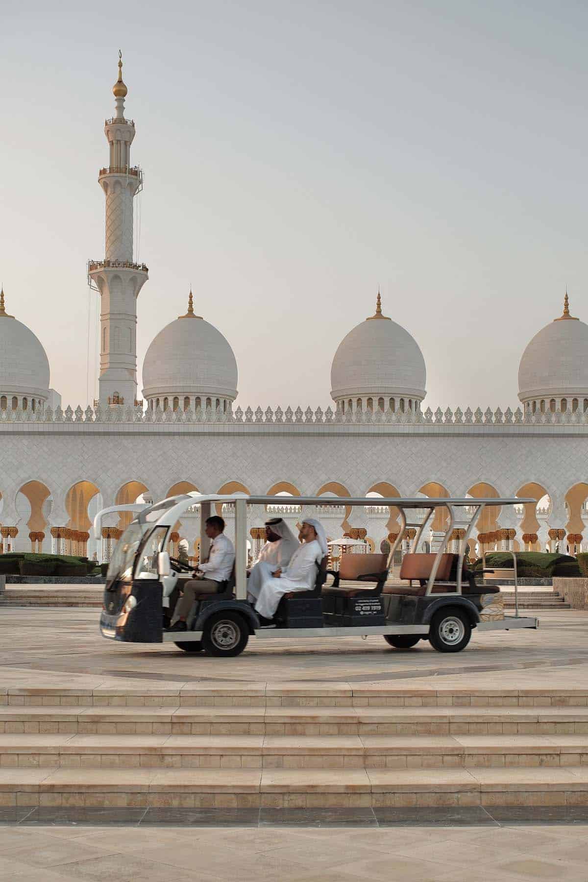 An image of a transport buggy in front of the Grand Mosque in Abu Dhabi at sunset