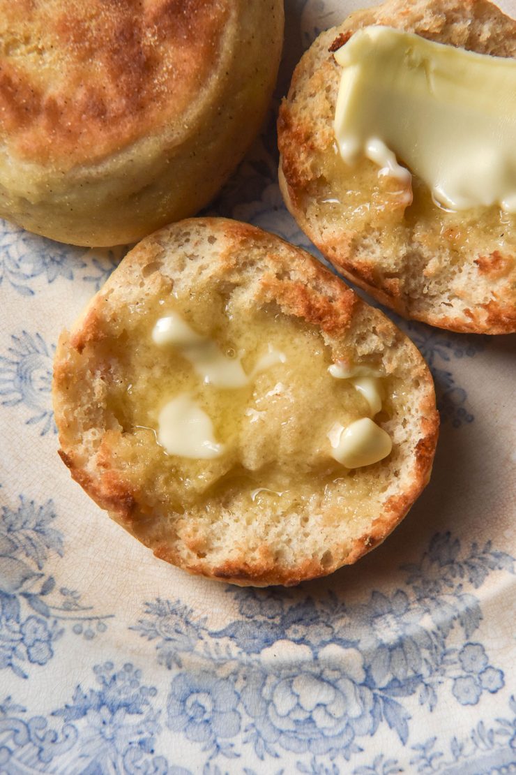 An aerial image of toasted and buttered gluten free English muffins on a blue and white patterned plate
