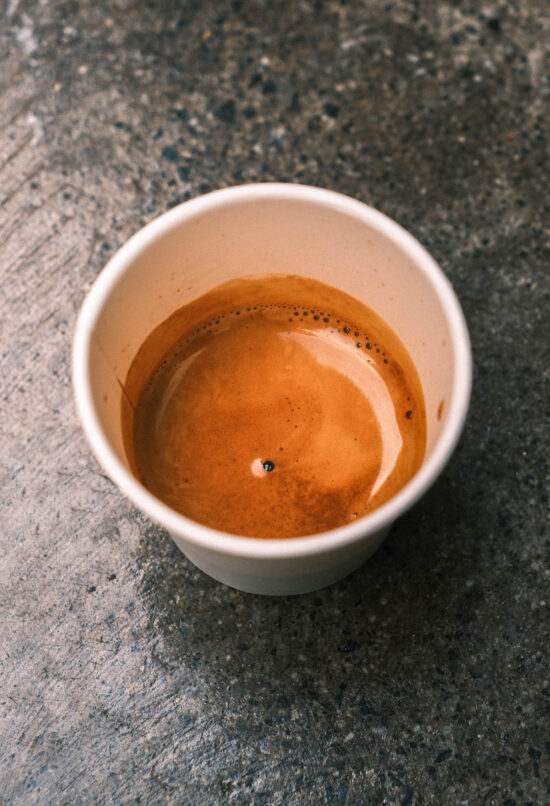 A close up image of an espresso on a mottled concrete backdrop