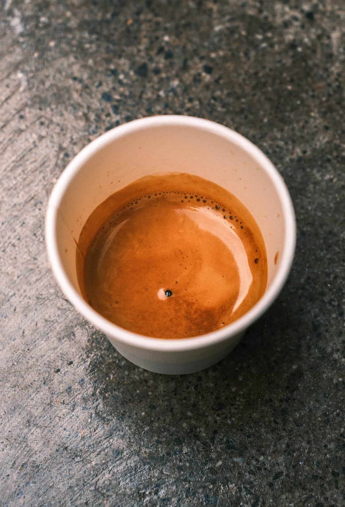 A close up image of an espresso on a mottled concrete backdrop