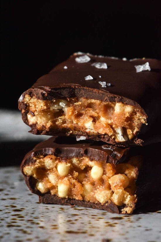 A macro side on image of a protein crisp bar that has been sliced in half and stacked on a white speckled ceramic plate