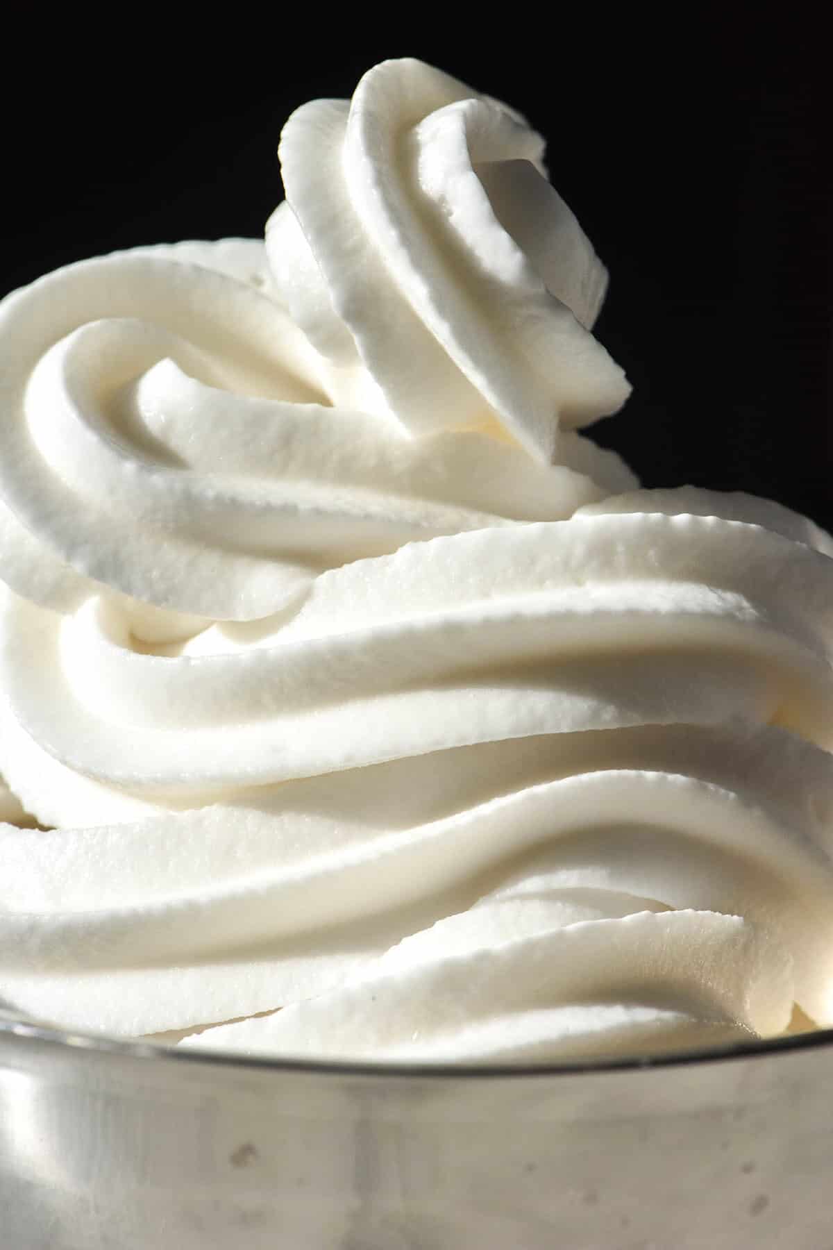 A close up macro image of a Ninja Swirl coconut yoghurt soft serve in a silver coupe against a dark backdrop