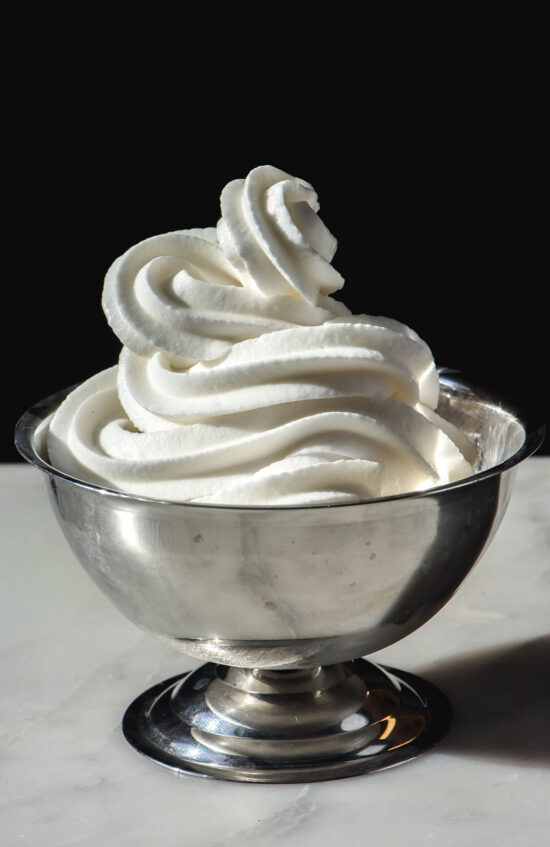 A side on image of a silver coupe filled with Ninja swirl frozen yoghurt. The coupe sits on a white table against a dark backdrop