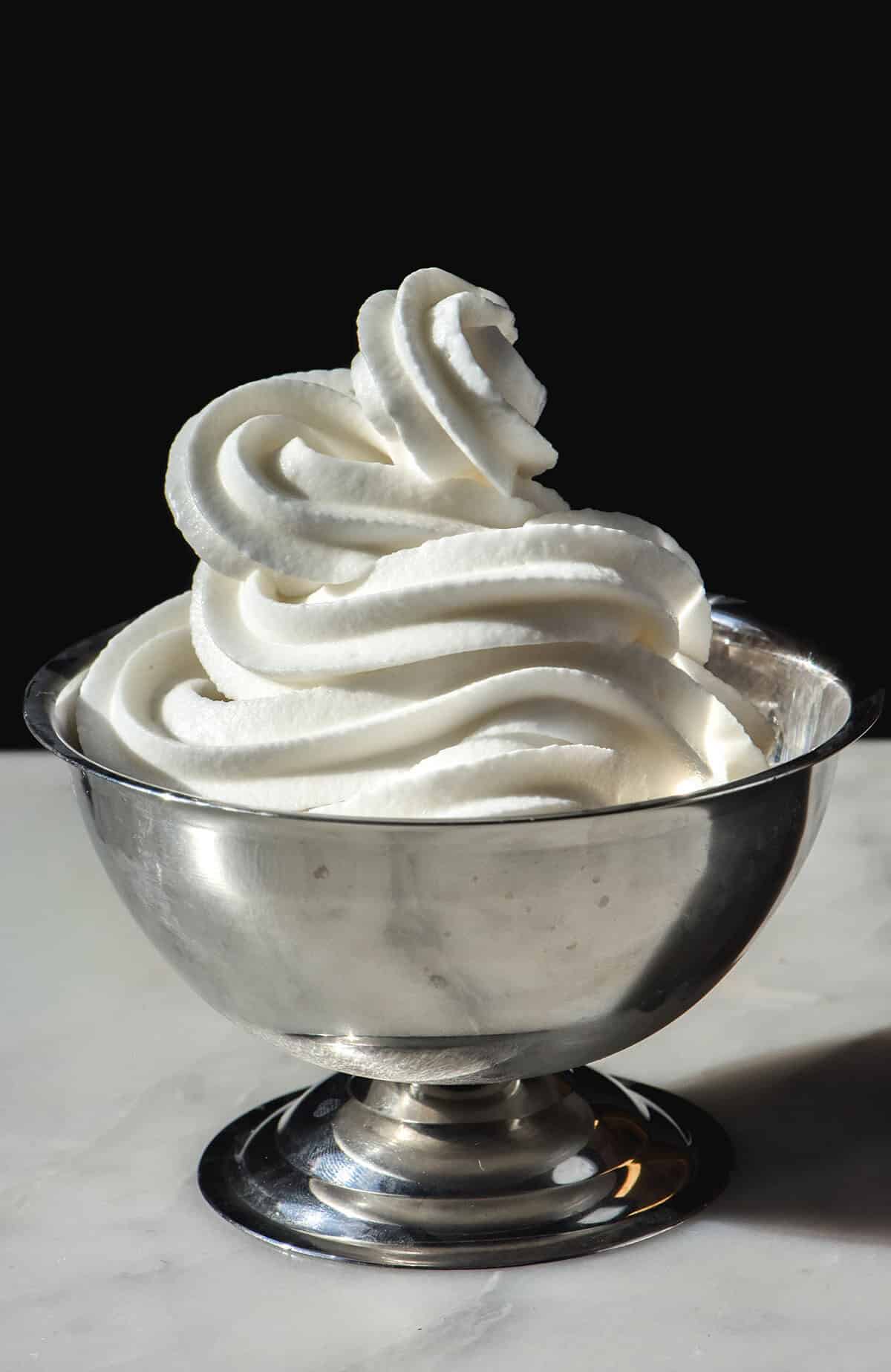A side on image of a silver coupe filled with Ninja swirl frozen yoghurt. The coupe sits on a white table against a dark backdrop