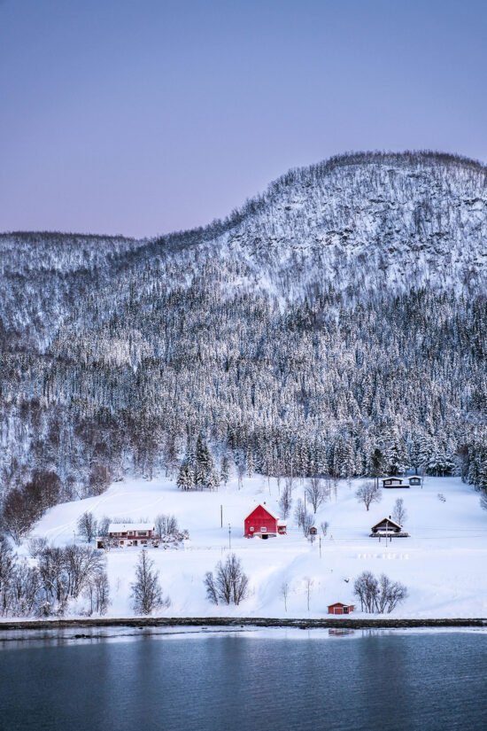 an image of a red rorbu house surrounded by a snowy scene in coastal Norway