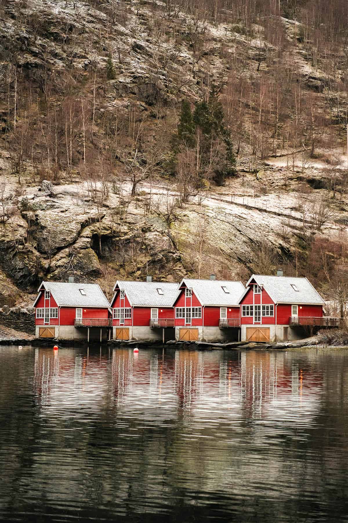 An image of the rorbu by the water in Flåm, Norway on a snowy day