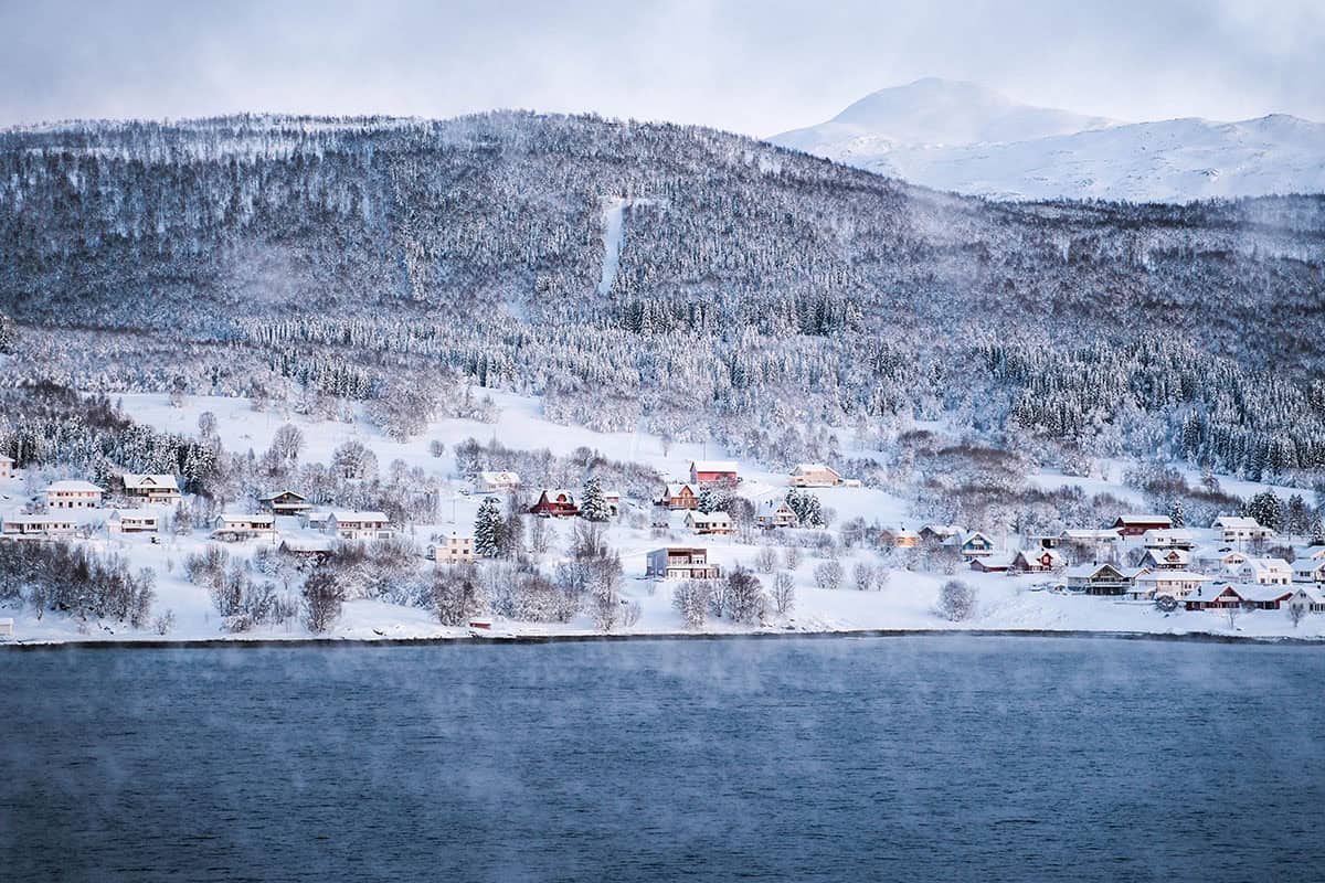 An image of a snowy coastal village in Norway as seen from Havila Polaris cruising up the coast