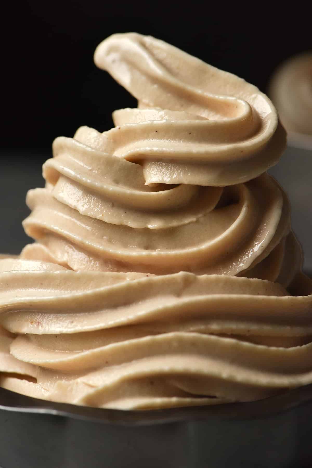 A close up image of a dessert coupe piled high with Ninja Swirl high protein soft serve against a dark backdrop
