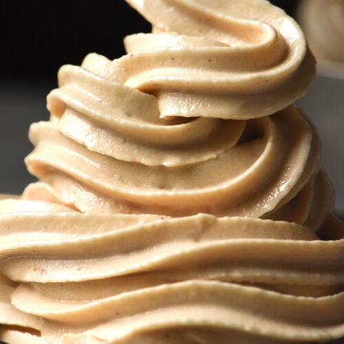 A close up image of a dessert coupe piled high with Ninja Swirl high protein soft serve against a dark backdrop