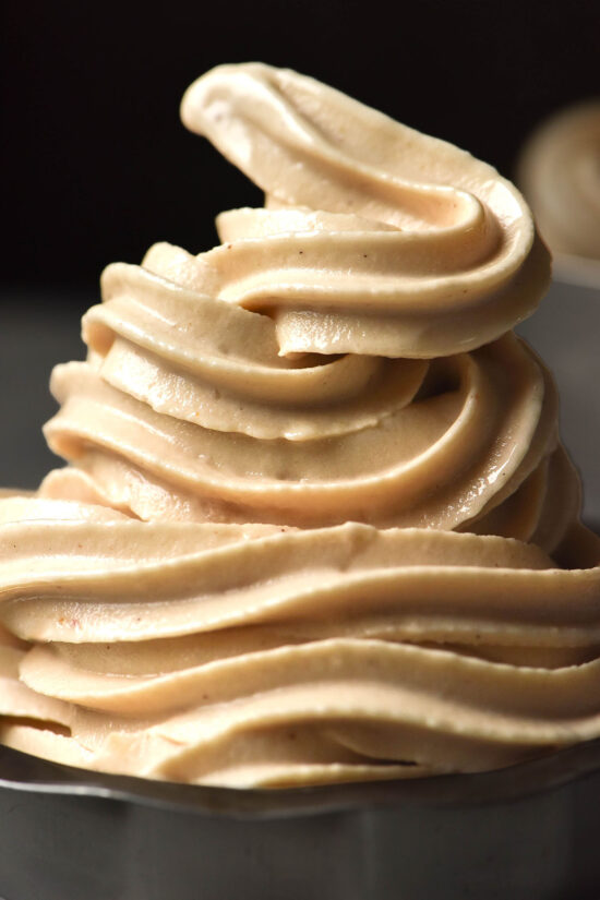 A close up image of a dessert coupe piled high with Ninja Swirl high protein soft serve against a dark backdrop