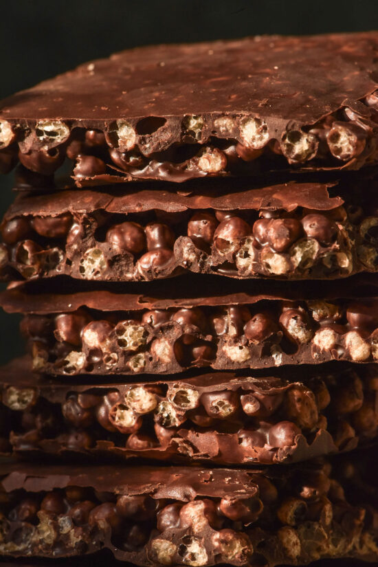 A macro close up side on view of a stack of protein crisp chocolate against a dark backdrop