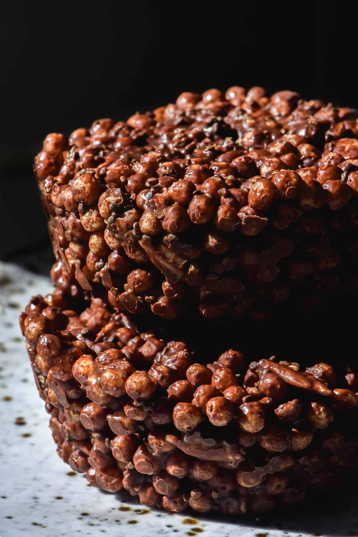 A moody side on image of two high protein rice krispies stacked on a white ceramic plate