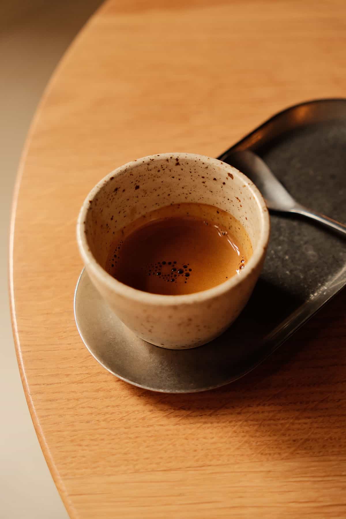 An image of an espresso in a ceramic cup on a wooden table at Barnum in Rome, Italy