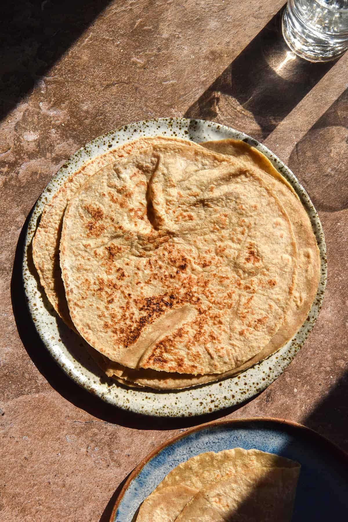 An aerial image of gluten free sourdough wraps on a brown backdrop in contrasting sunlight